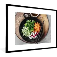 PosterMonkey Fotolijst incl. Poster - Een kom groenten met kruiden en hartige saus op een houten snijplank - 80x60 cm - Posterlijst