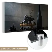 MuchoWow Glasschilderij 120x60 cm - Schilderij acrylglas - Stilleven - Zwart - Fles - Druiven - Foto op glas - Muurdecoratie woonkamer - Wanddecoratie slaapkamer - Schilderijen