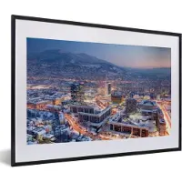 MuchoWow Foto in lijst - Straatbeeld van Sarajevo en berg met sneeuw in Bosnië en Herzegovina fotolijst zwart met witte passe-partout 60x40 cm - Poster in lijst (Wanddecoratie woonkamer / slaapkamer)